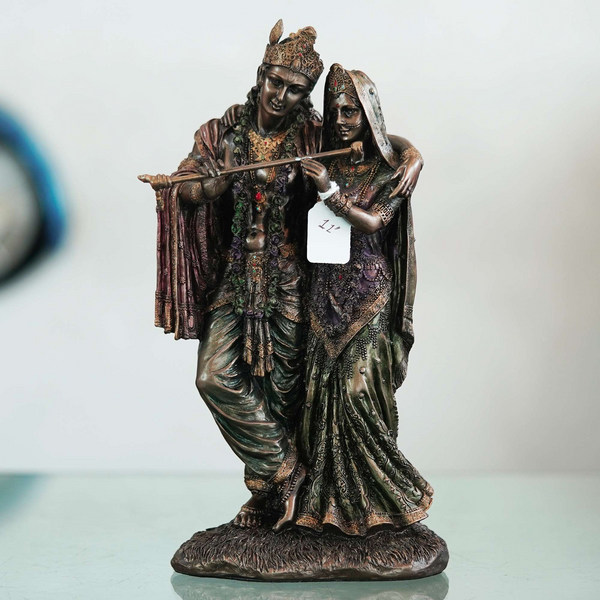 A beautiful and intricate bronze statue depicting Radha and Krishna, two central deities in Hinduism